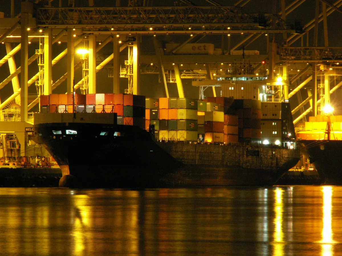 Container ship under gantry cranes at a port at night